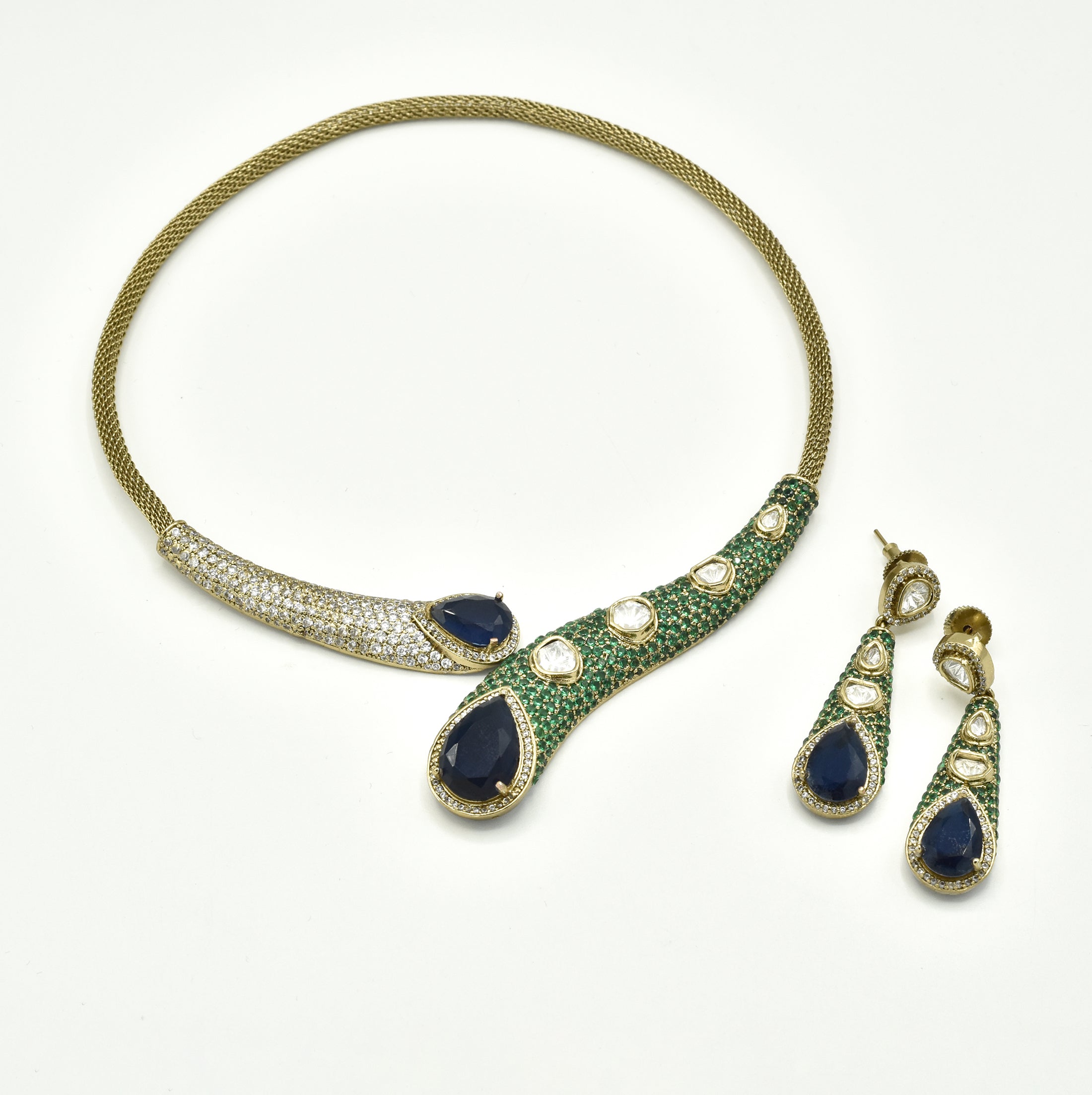 Contemporary gold-tone Hasli necklace set with deep blue teardrop stones, green pavé-style detailing, Kundan-inspired accents and matching long earrings.