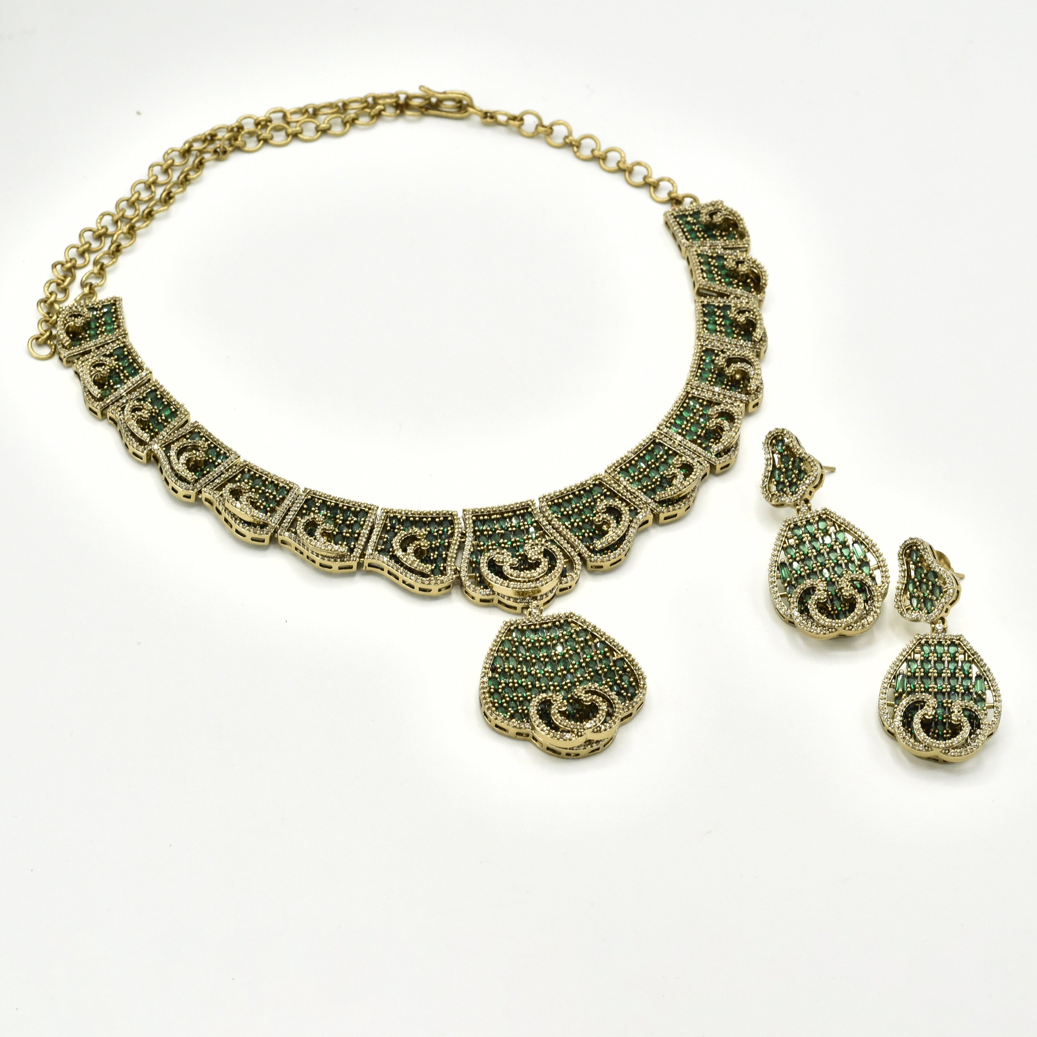 Antique gold-tone green stone statement necklace featuring intricate geometric detailing, sparkling crystal accents, teardrop pendant and matching drop earrings.