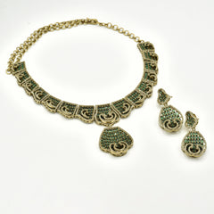 Antique gold-tone green stone statement necklace featuring intricate geometric detailing, sparkling crystal accents, teardrop pendant and matching drop earrings.