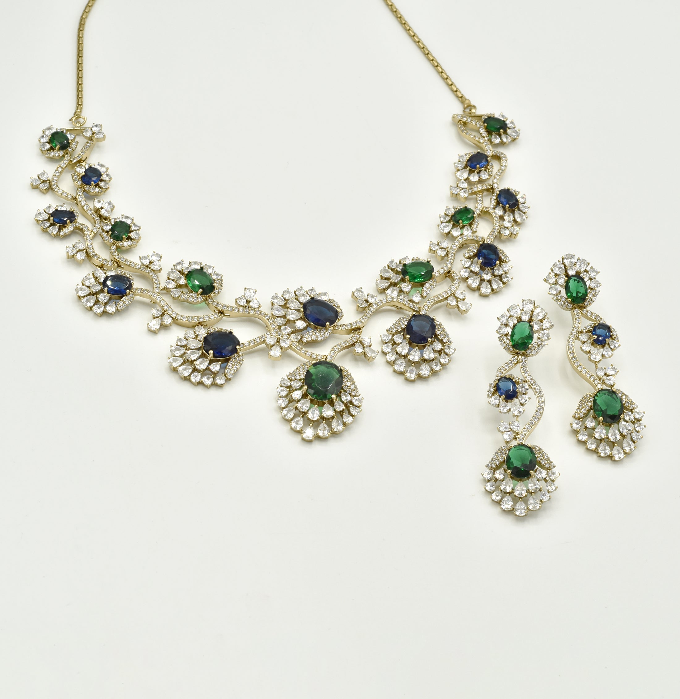 Blue and green American Diamond necklace set with gold-tone floral vine detailing, sparkling clear stones and matching long statement earrings.