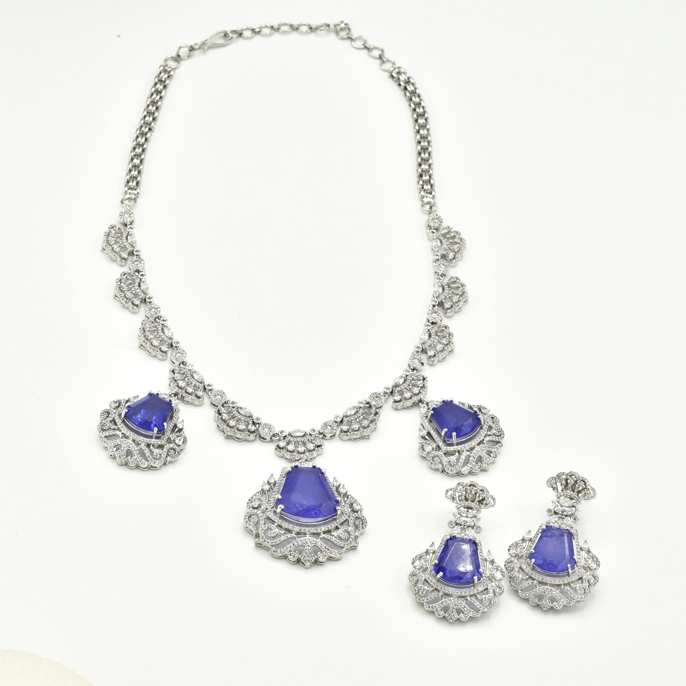 Purple American Diamond statement necklace set with three violet-purple stone drops, intricate silver-tone crystal detailing, and matching statement earrings.